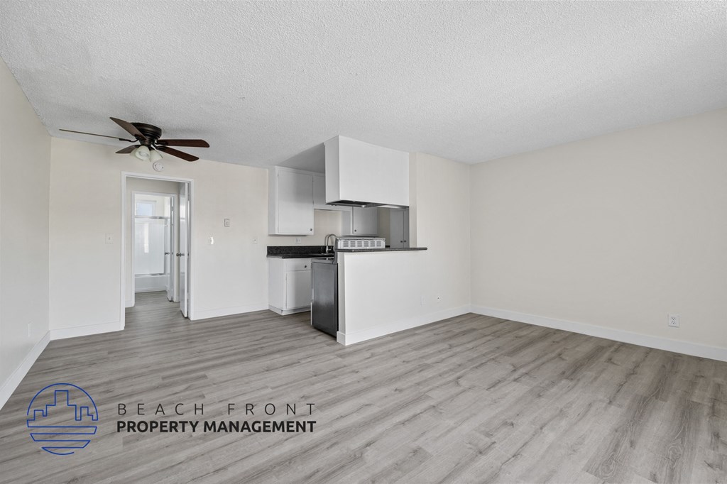 A spacious kitchen with white cabinets and a wooden floor.