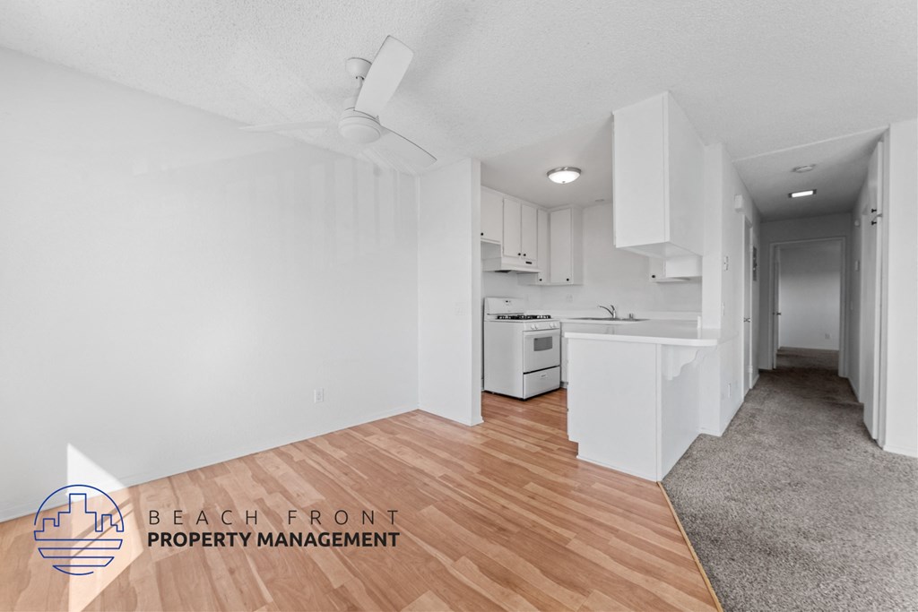 A spacious, empty room with a kitchenette and a dining table.