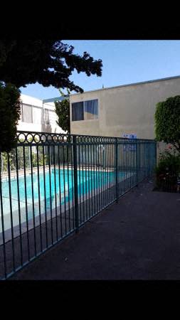 a swimming pool behind a fence with a building in the background