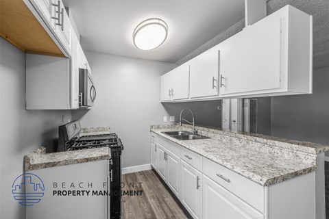A kitchen with white cabinets and a granite countertop.