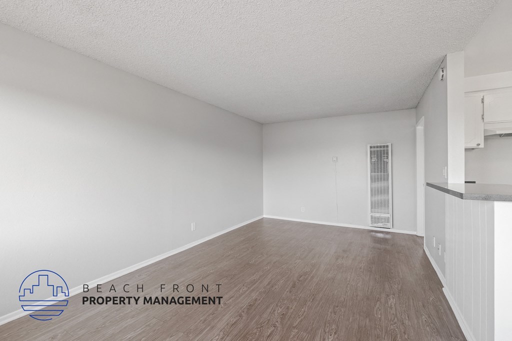 the spacious living room with wood flooring and white walls