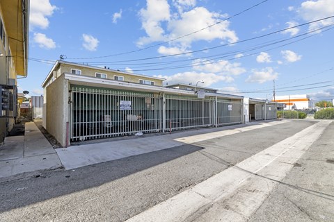 A large, empty parking lot with a building and a gate in the background.