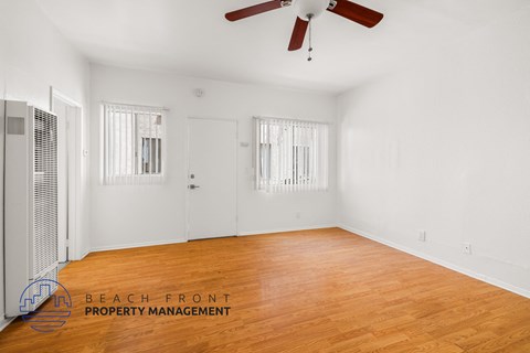 a living room with wood floors and white walls and a ceiling fan