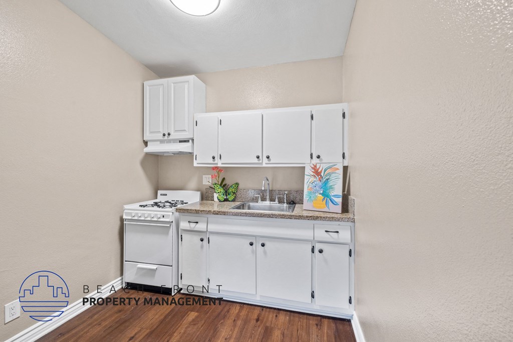 a kitchen with white cabinets and a sink and a stove