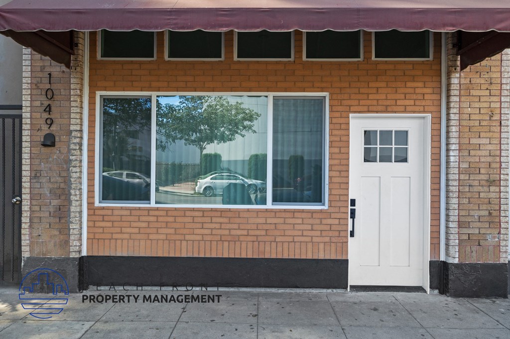 the front of the property management office with a car reflection in the window