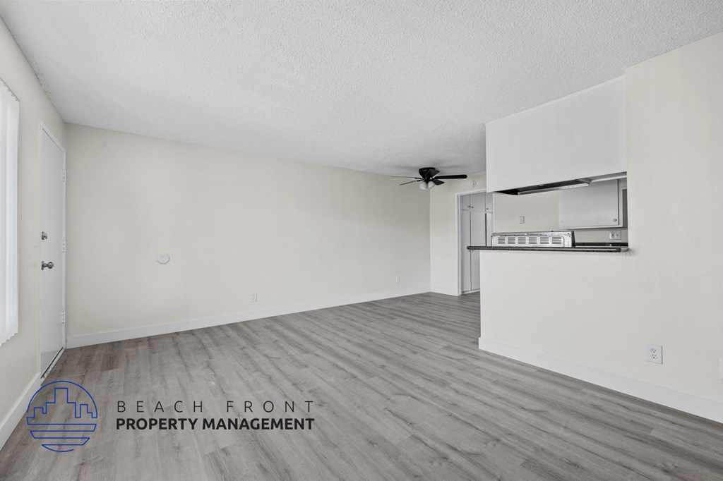 A spacious room with a ceiling fan and a wall-mounted shelf.