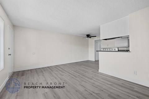 A spacious room with a ceiling fan and a wall-mounted shelf.