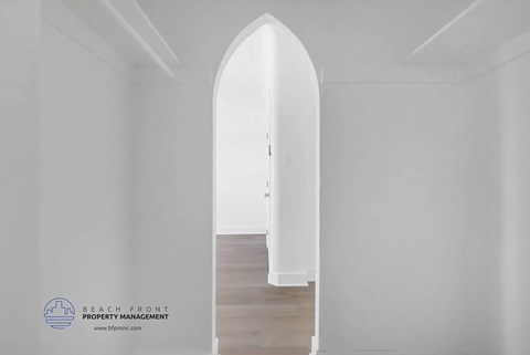 A white hallway with a wooden floor and a white door.