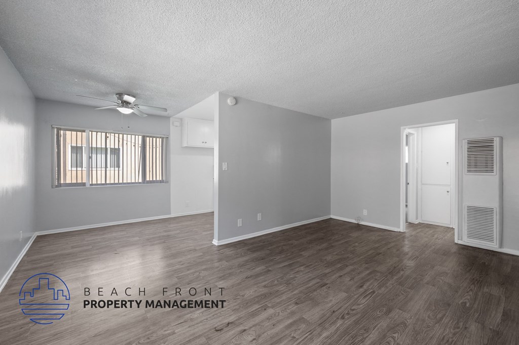 the spacious living room with hardwood flooring and a ceiling fan