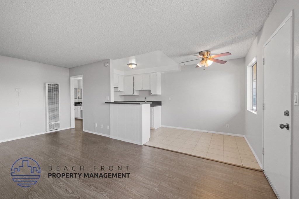 an empty living room and kitchen with a ceiling fan