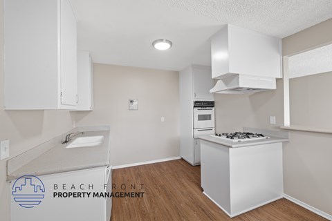 A kitchen with a white stove top oven and white cabinets.