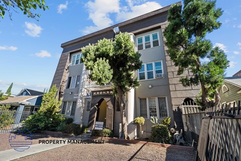a gray building with a gate and trees in front of it