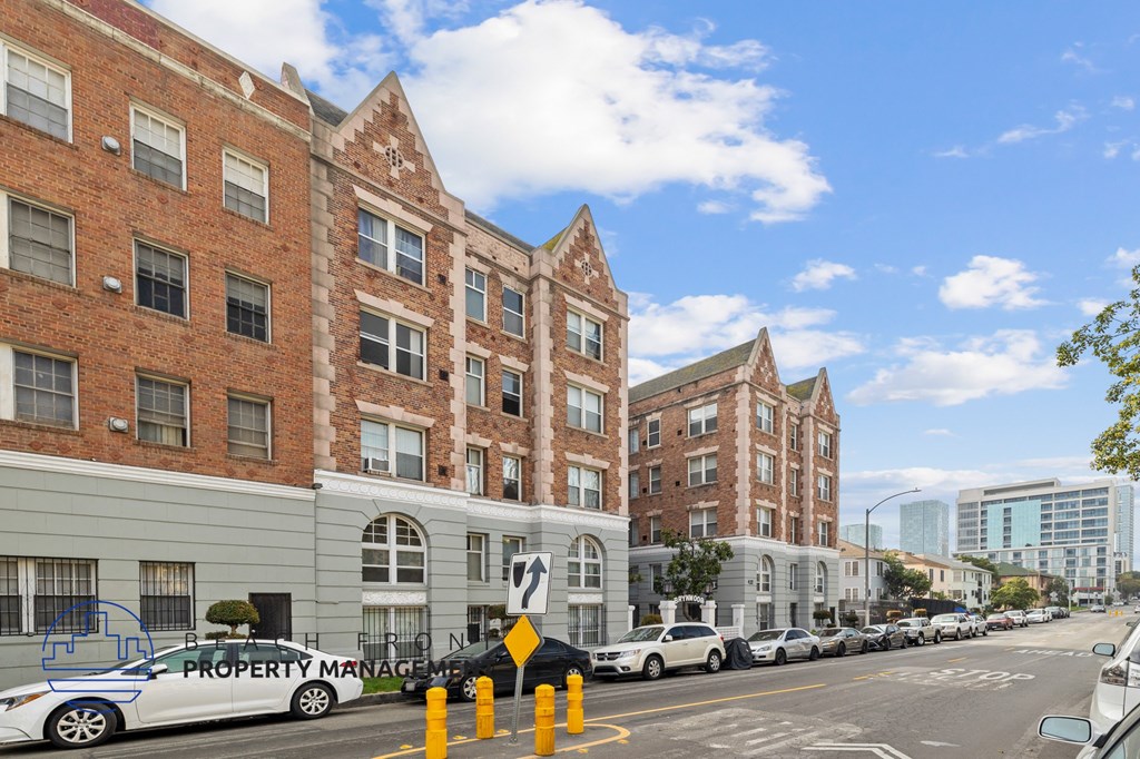 A street view of a row of buildings with cars parked on the side.