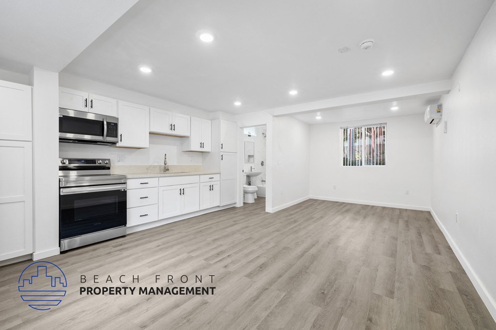 A spacious kitchen with white cabinets and a wooden floor.
