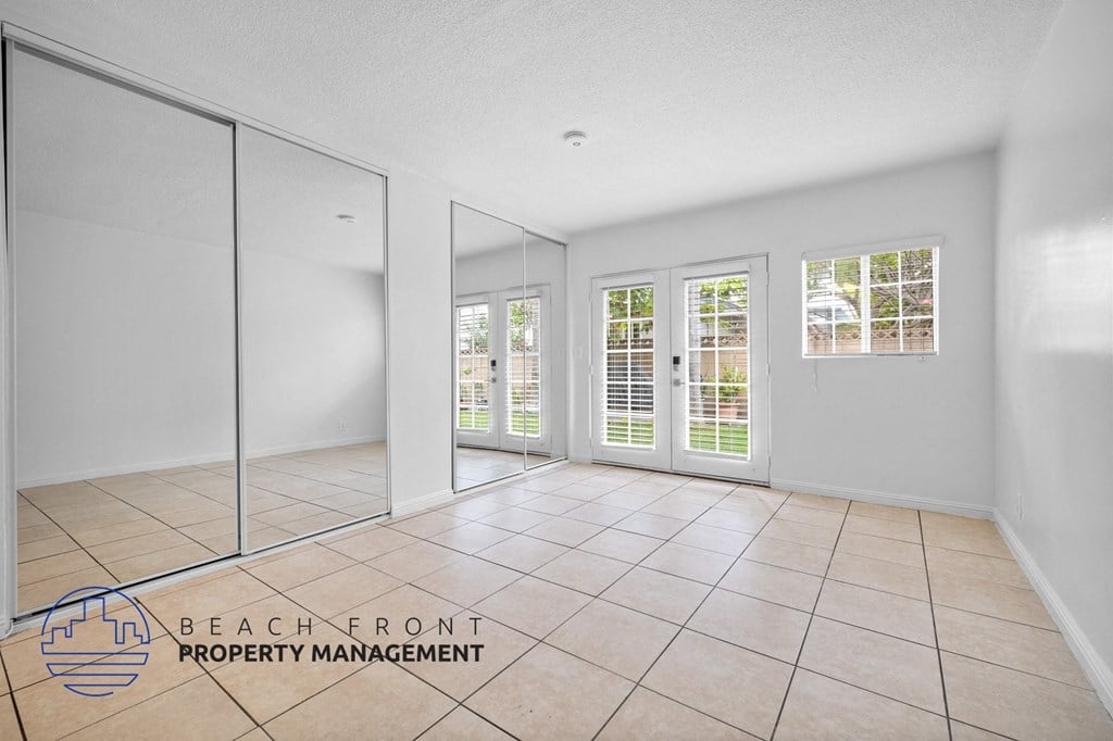 the living room and dining room of a house with white walls and tiled floors