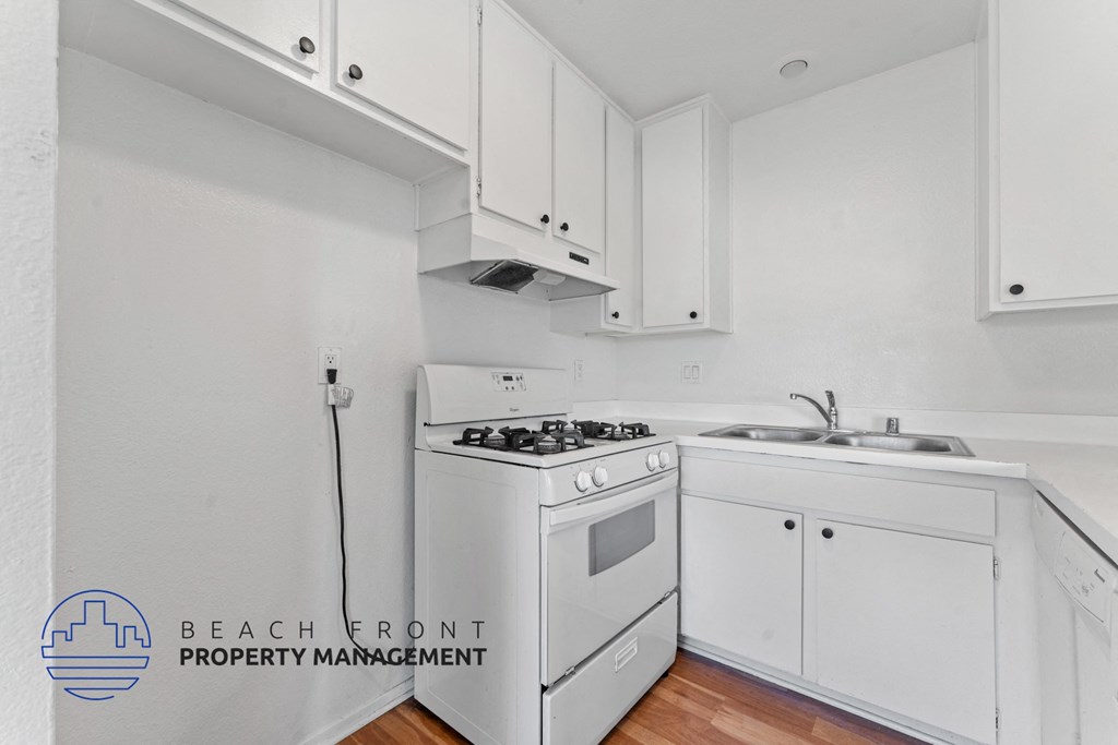 A white kitchen with a stove and sink.