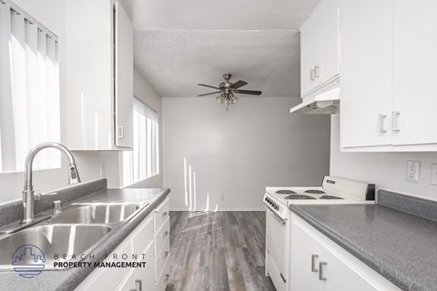 A kitchen with white cabinets and a stainless steel sink.