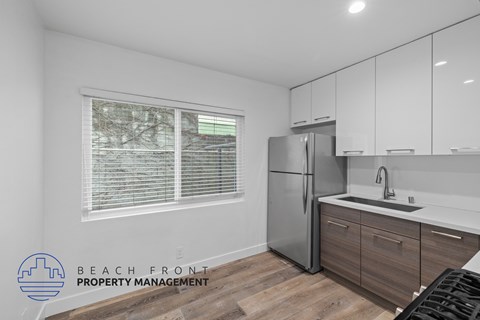 A kitchen with a refrigerator, sink, and cabinets.