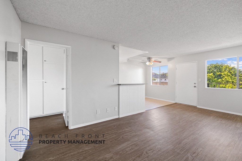 the living room and dining room of an apartment with white walls and wood floors