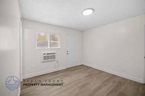the living room of an apartment with white walls and wood flooring