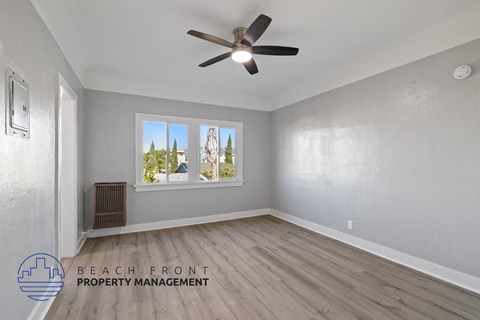 an empty living room with a ceiling fan and a window