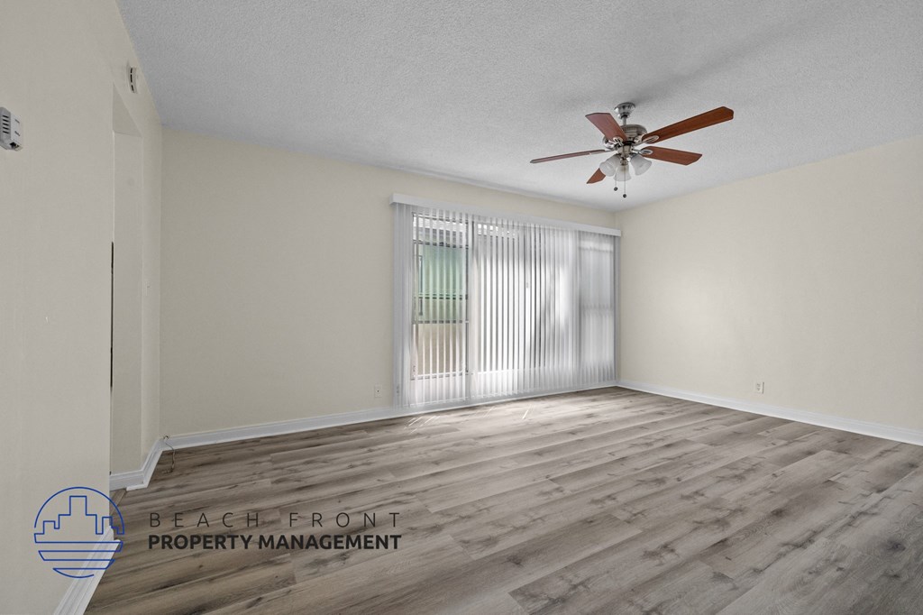 the spacious living room with wood flooring and a ceiling fan