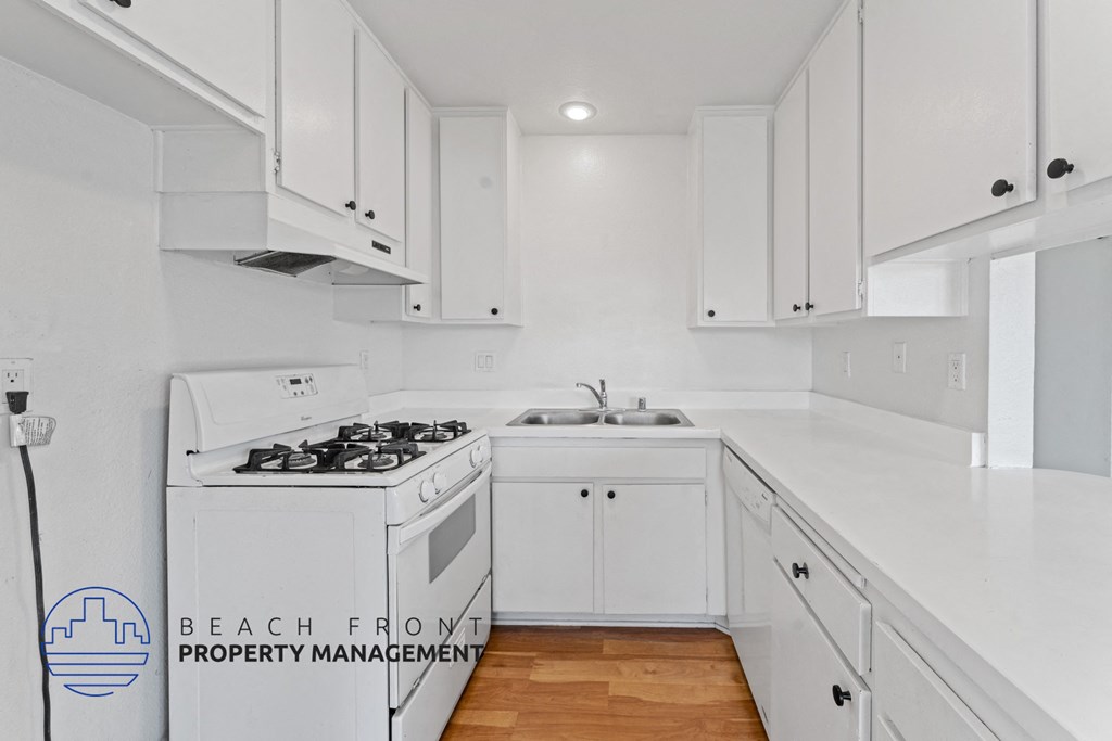 A kitchen with white cabinets and a stove top oven.