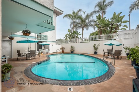 A pool surrounded by chairs and umbrellas with a sign that says "Beach from Property Management".