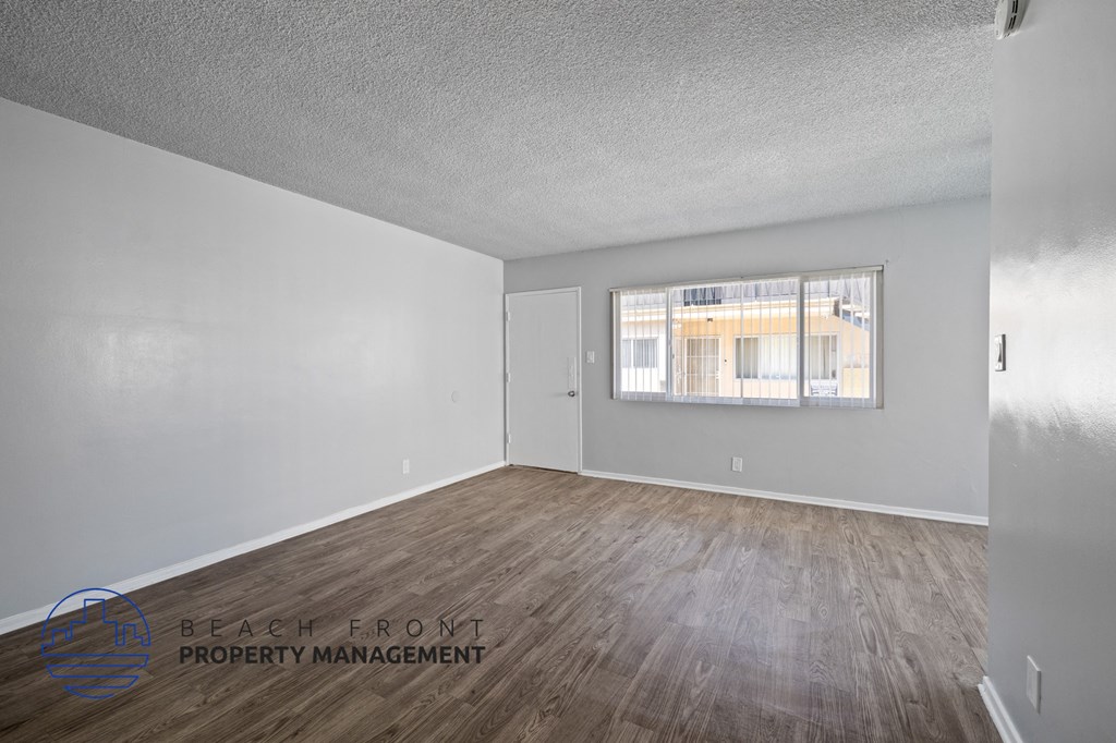the living room of an apartment with wood flooring and a window