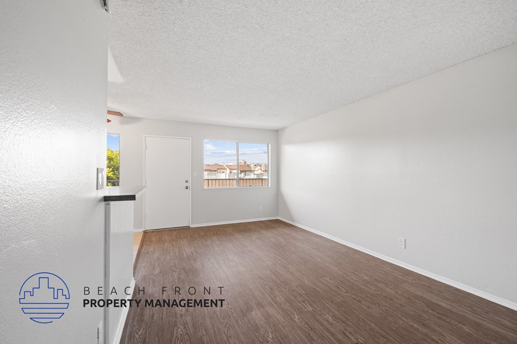 an empty living room with wood flooring and a window