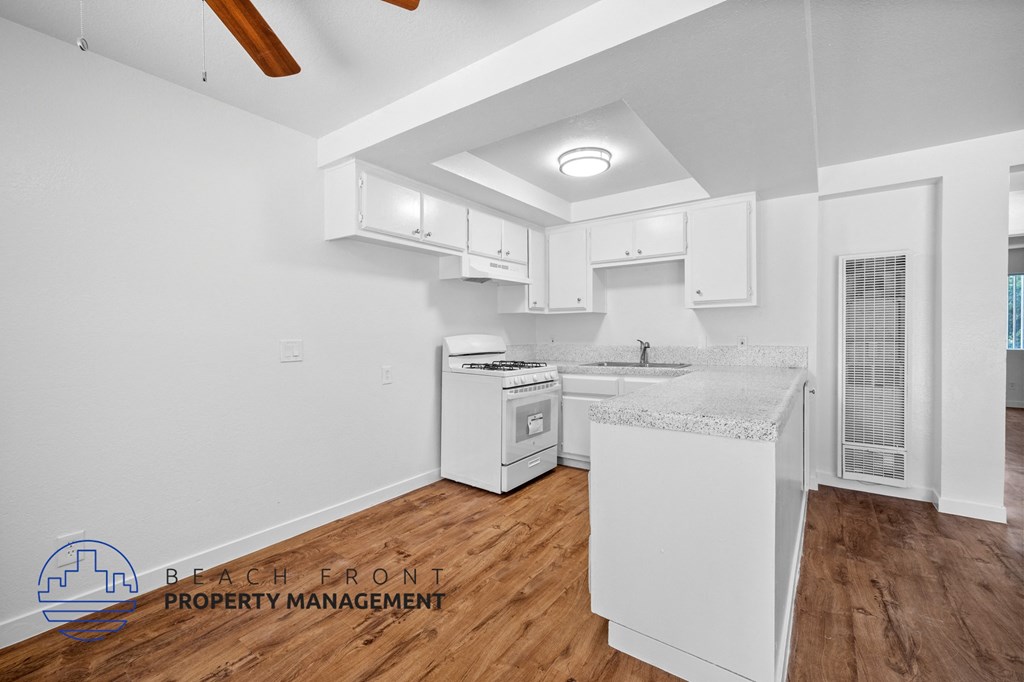 a kitchen with white cabinets and white appliances and wood floors