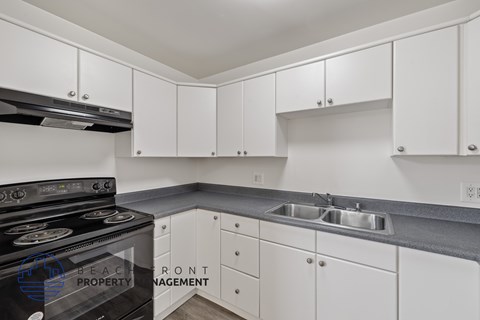 A kitchen with white cabinets and a black stove top oven.