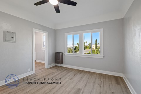 an empty living room with a window and a ceiling fan