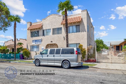 a silver van parked in front of a building with palm trees