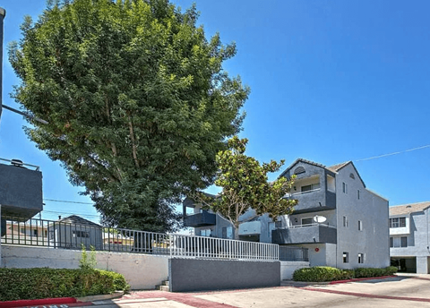 A large grey building with a tree in front of it.