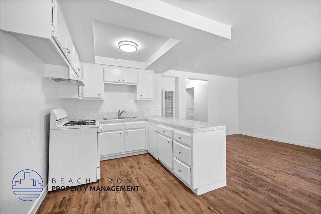 a white kitchen with a wooden floor and white cabinets