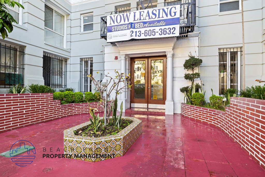 A building with a sign that says "NOW LEASING" and a phone number.