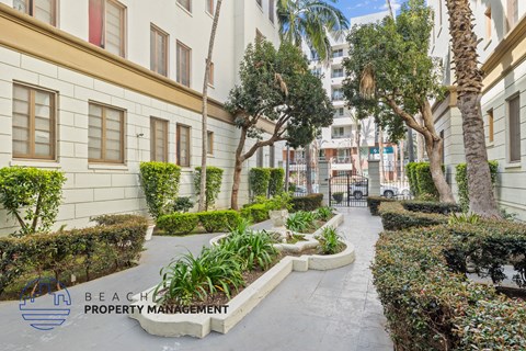 A well-maintained garden pathway with a variety of plants and trees.