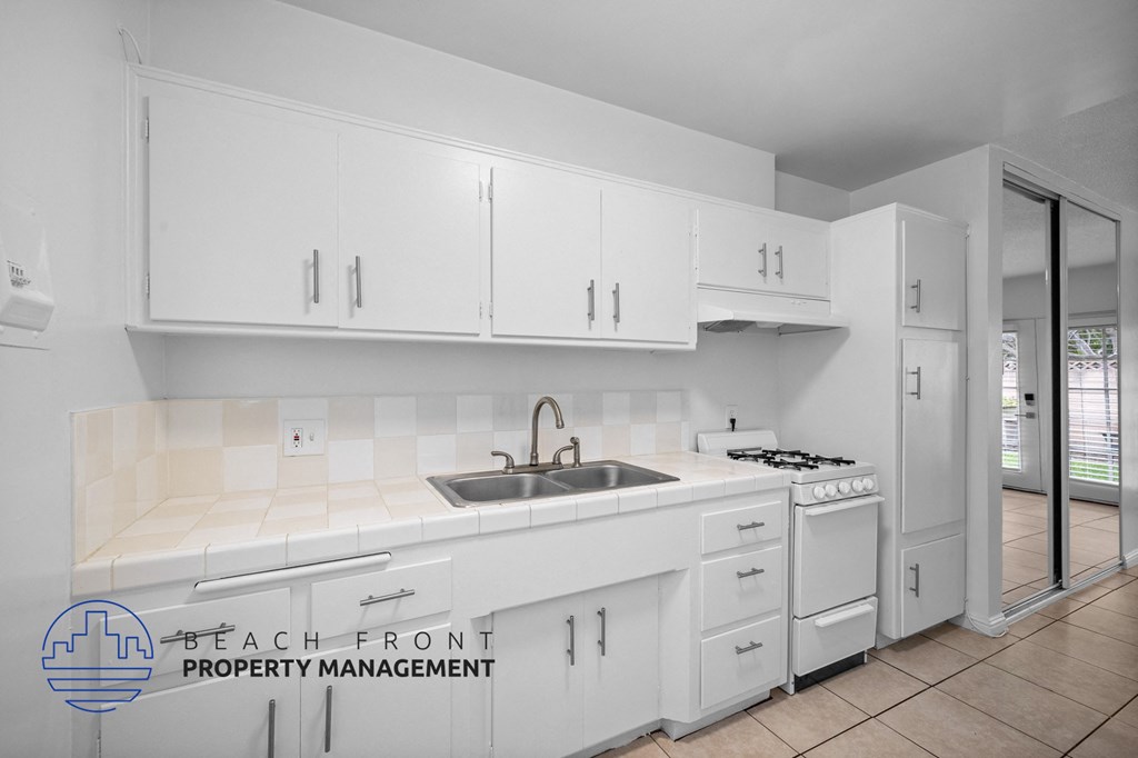 a white kitchen with white cabinets and a sink