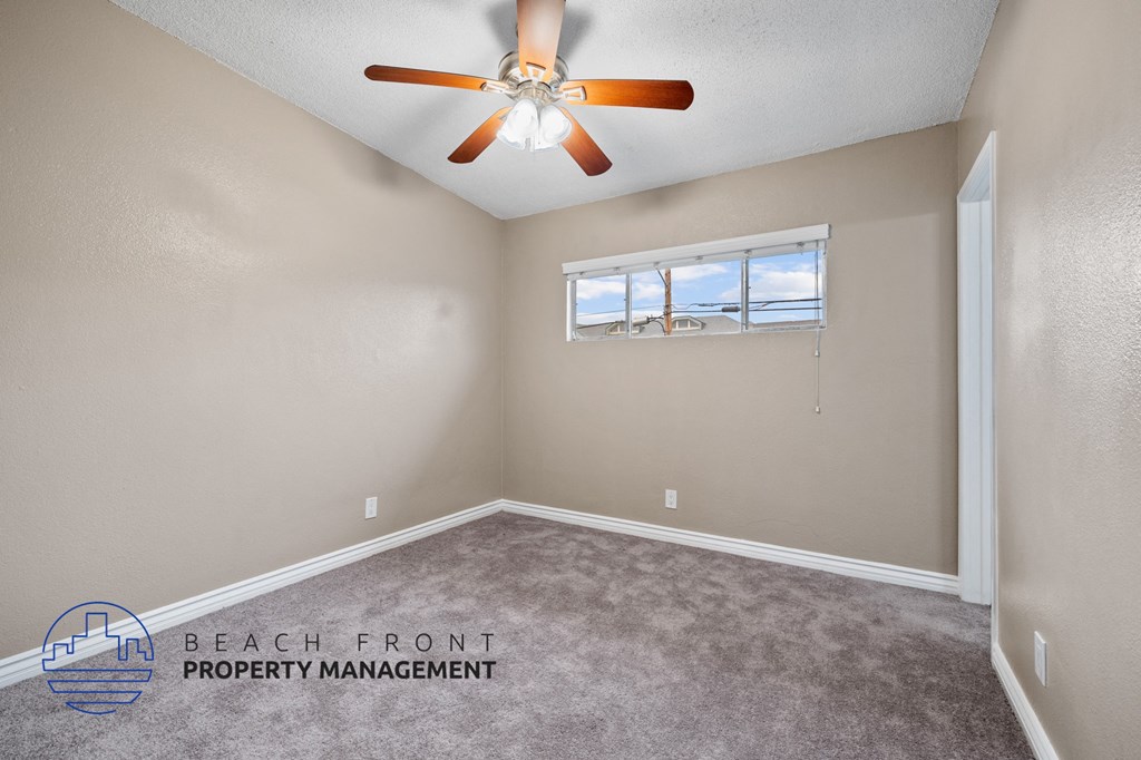 an empty bedroom with a ceiling fan and a window