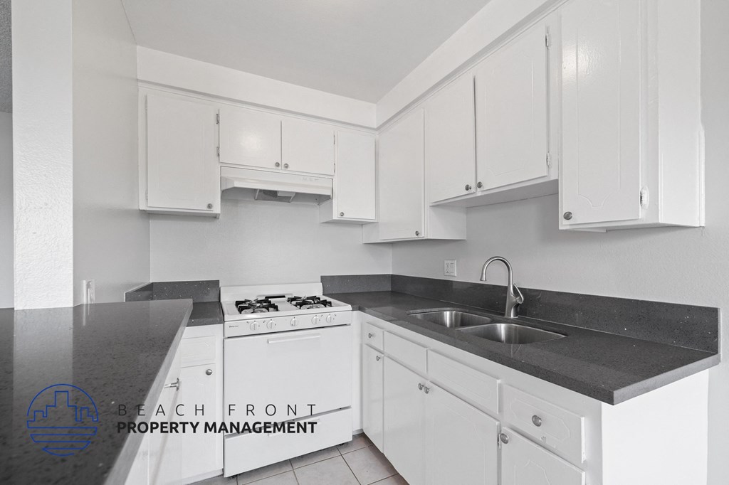 a white kitchen with white cabinets and black counter tops