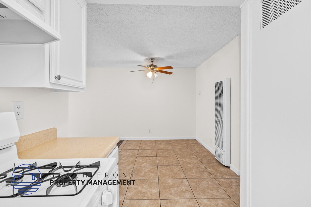 a kitchen with white cabinets and a ceiling fan