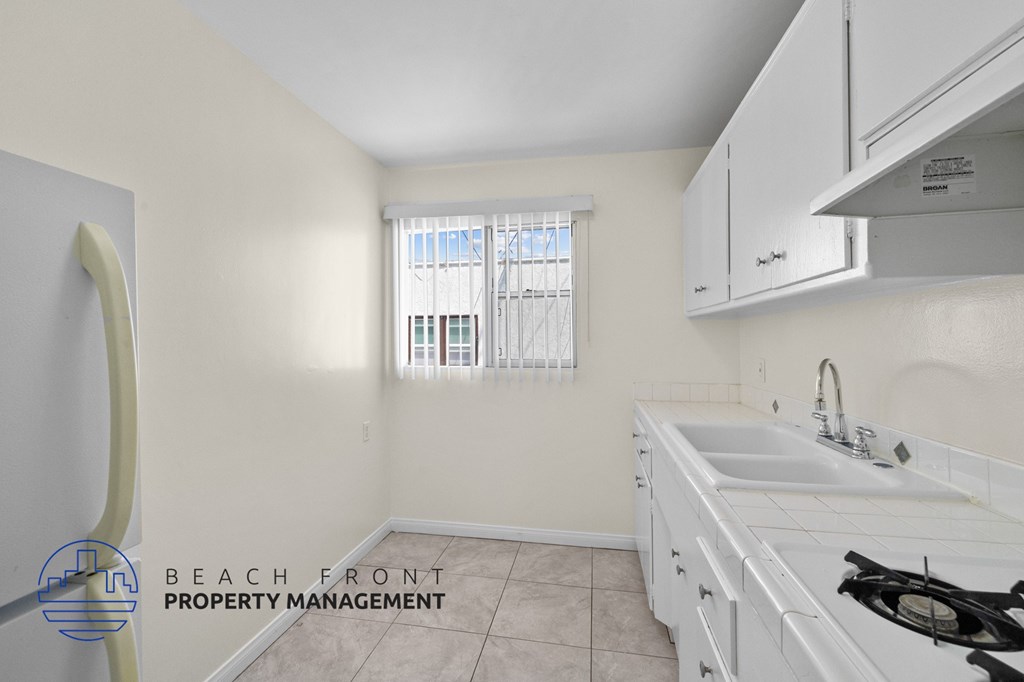 a kitchen with white cabinets and a sink and a window