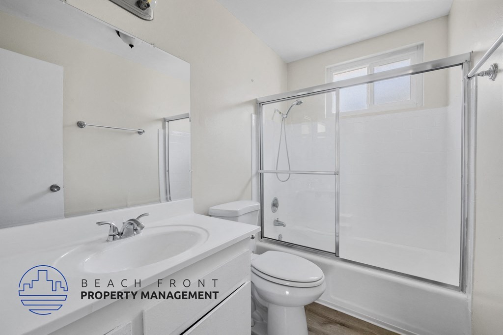 A white bathroom with a sink, toilet, and shower.