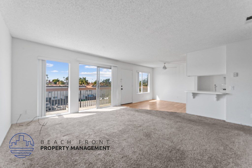 A room with a carpet floor and a logo of Beach Front Property Management on the wall.