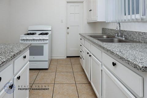 A kitchen with white cabinets and a granite countertop.