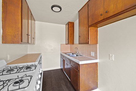 A kitchen with a stove top oven and wooden cabinets.
