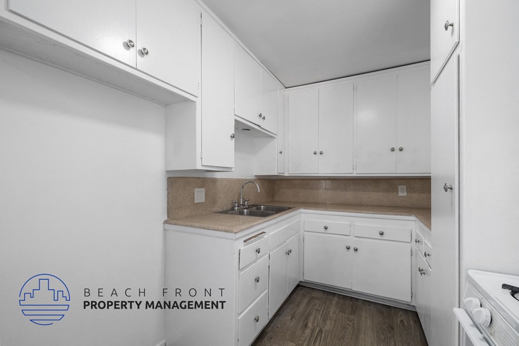 a kitchen with white cabinets and white appliances and a sink