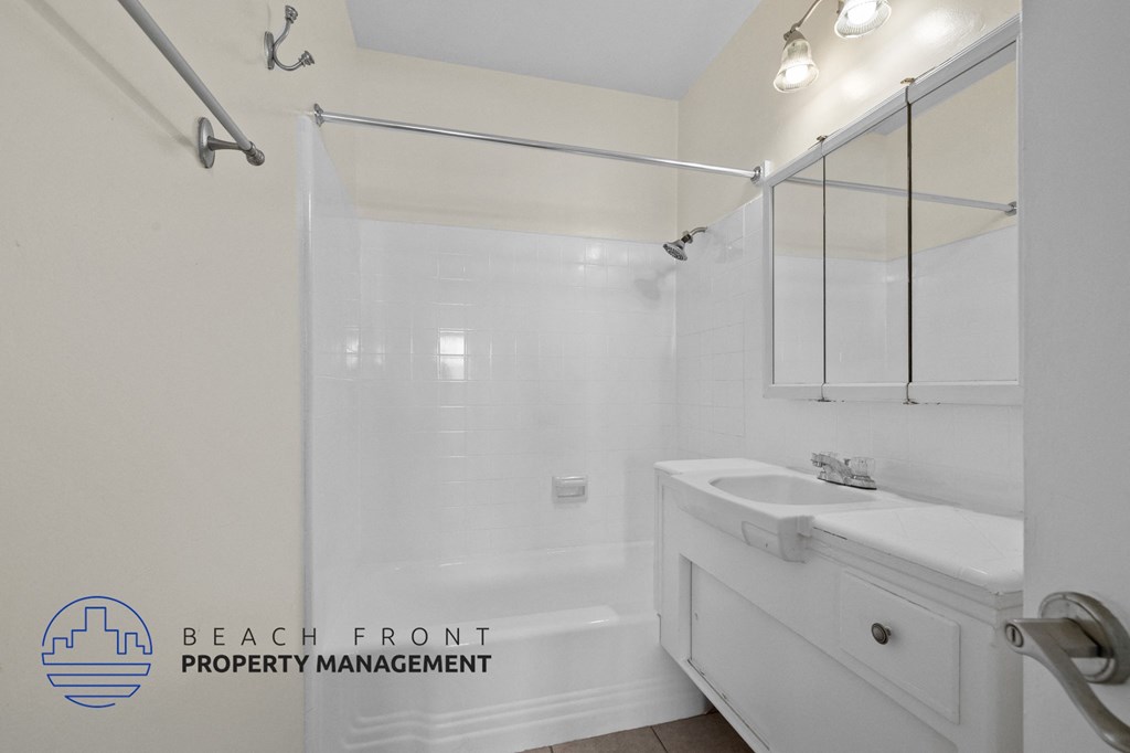 a white bathroom with a shower and a sink and a mirror
