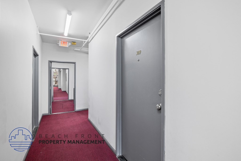 A hallway with a red carpet and a door on the right.